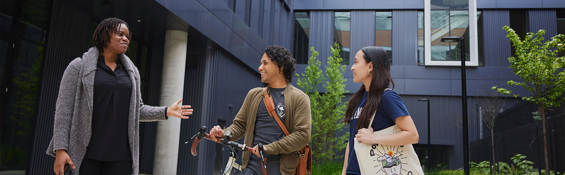 Three students talking together on a campus walkway.