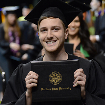 A student holding a degree at commencement